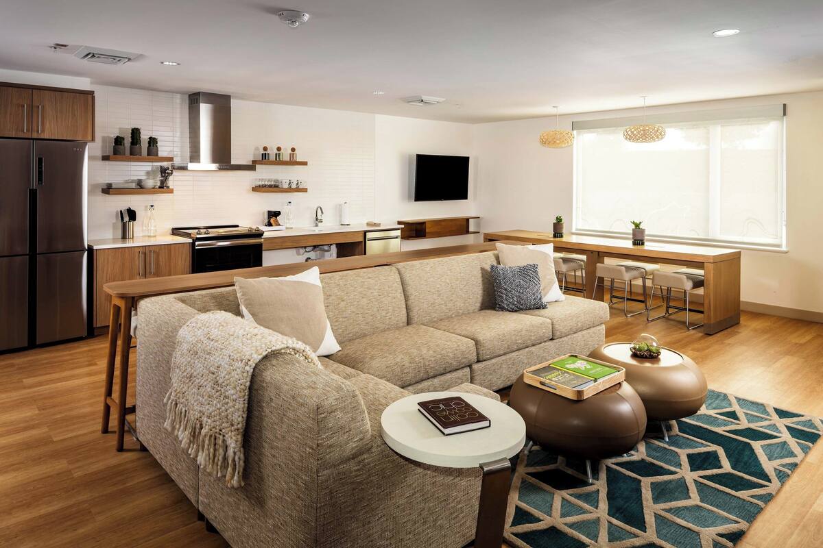 A modern living room with a sofa, coffee table, and a dining area with a table and chairs.