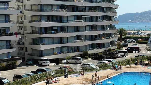 Un hôtel à plusieurs étages doté d’une piscine entourée de transats et de parasols.