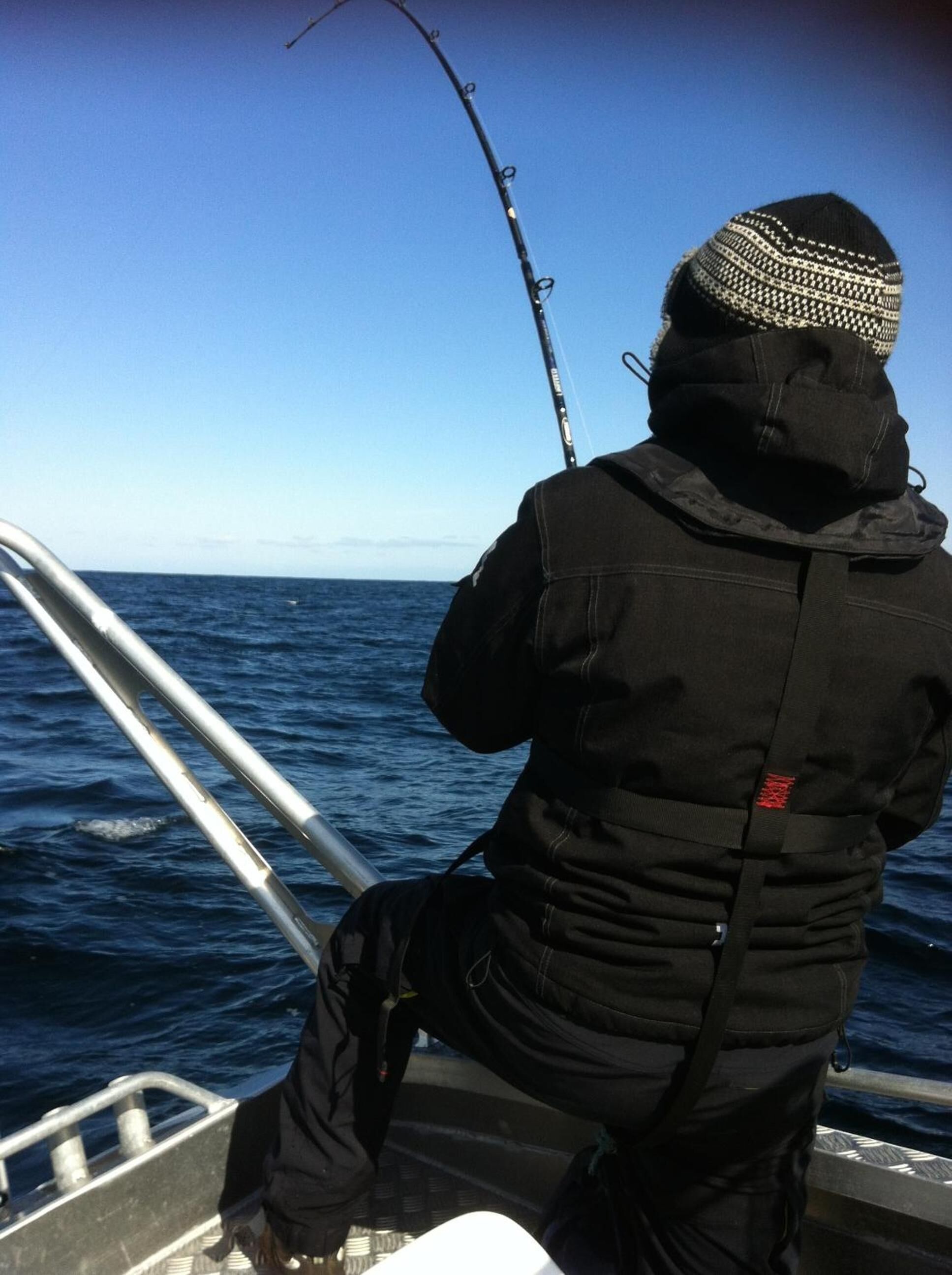 Una persona che pesca da una barca con vista sull'oceano.