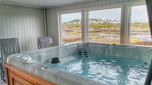 A hot tub with a view of a rocky landscape through large windows. - Sula Rorbuer og Havhotell (Frøya)