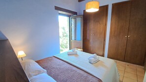 Ein Schlafzimmer mit einem Bett, zwei Nachttischlampen, einem Fenster und Holzschränken.