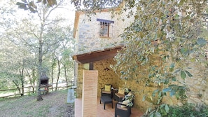 Ein rustikales Steinhaus mit Balkon, Sitzgelegenheiten im Freien und Grillbereich.