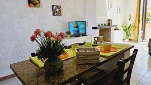 Een keuken met granieten aanrecht, een eettafel met stoelen, een televisie en diverse keukenbenodigdheden.