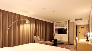 Une chambre d’hôtel avec un grand lit, un bureau, une chaise, une télévision et une porte.