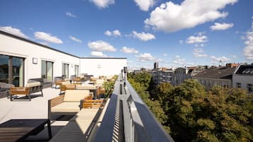 Una terraza en la azotea con mobiliario exterior y vistas a la ciudad.