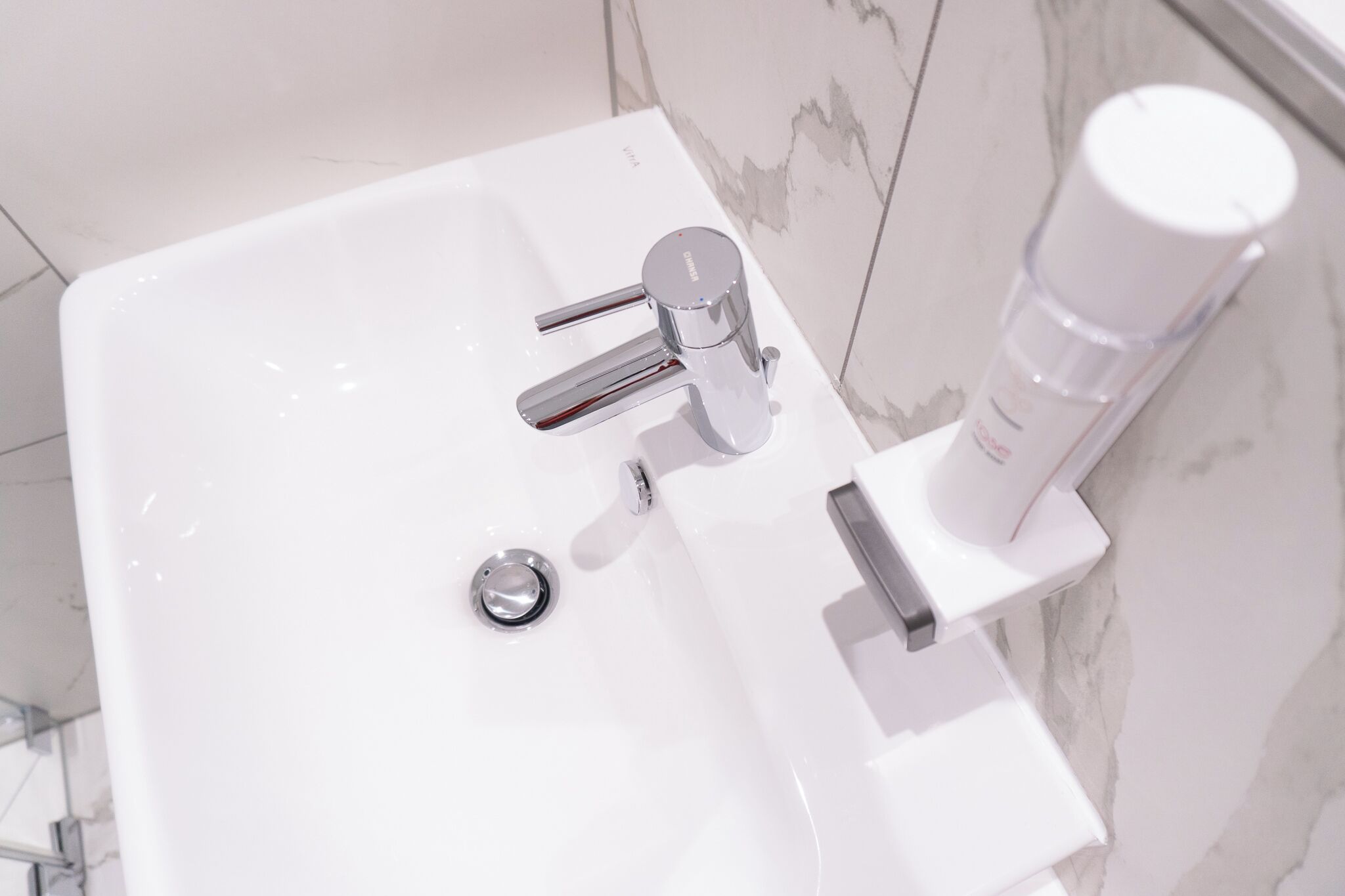 A modern bathroom sink with a chrome faucet and a soap dispenser.
