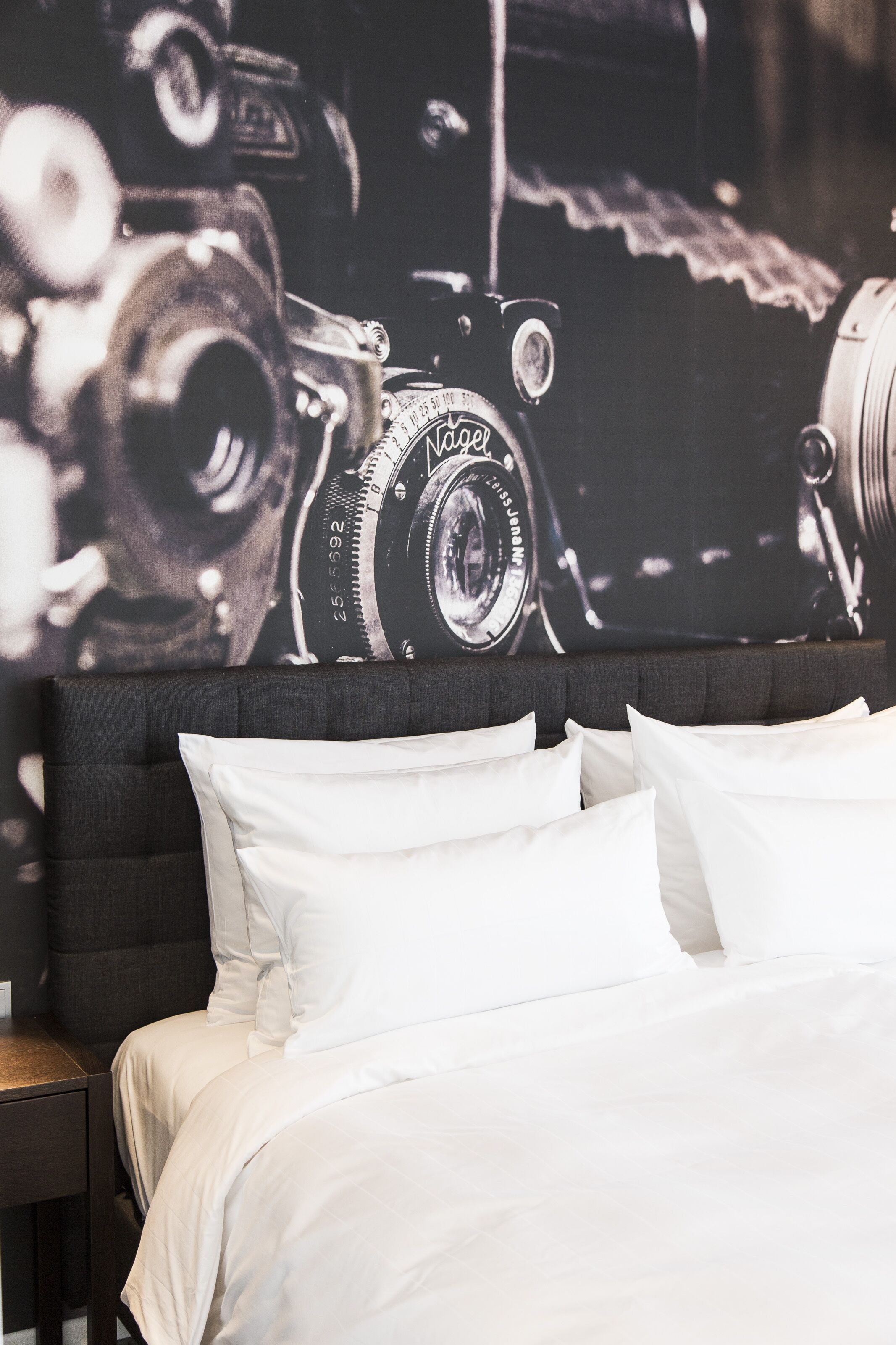 Un dormitorio con una cama grande, almohadas blancas y cabecera.