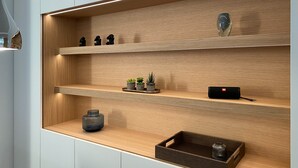 Une cuisine moderne avec des étagères en bois, une petite plante en pot et un haut-parleur noir.