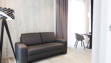 Habitación empresarial doble, 1 cama King size y sofá cama | Área de sala de estar | Televisión de pantalla plana de 42 pulgadas con canales vía satélite