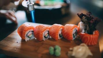 Une table en bois avec des sushis et un petit vase de fleurs.