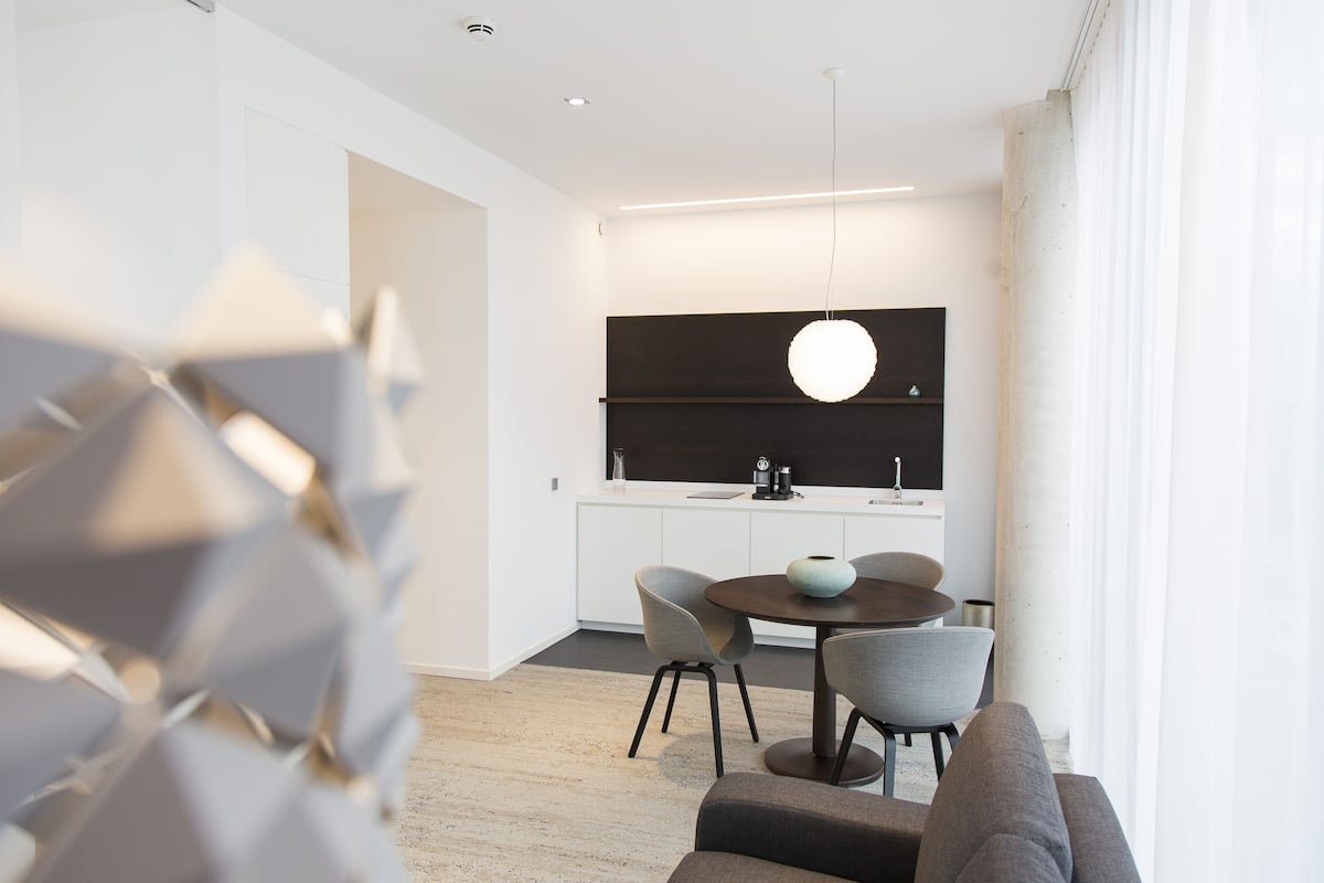 A modern kitchen with white cabinets, a black countertop, and a round dining table with chairs.