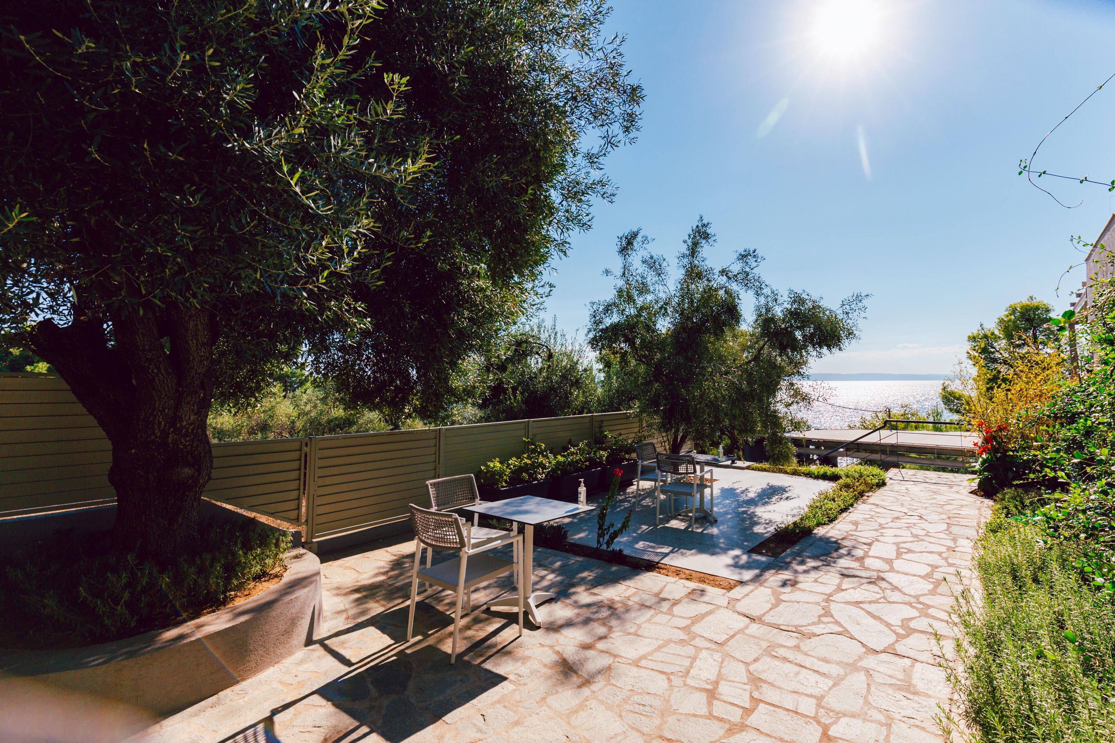 Un patio exterior con suelo de piedra, una mesa, sillas y vista al mar.