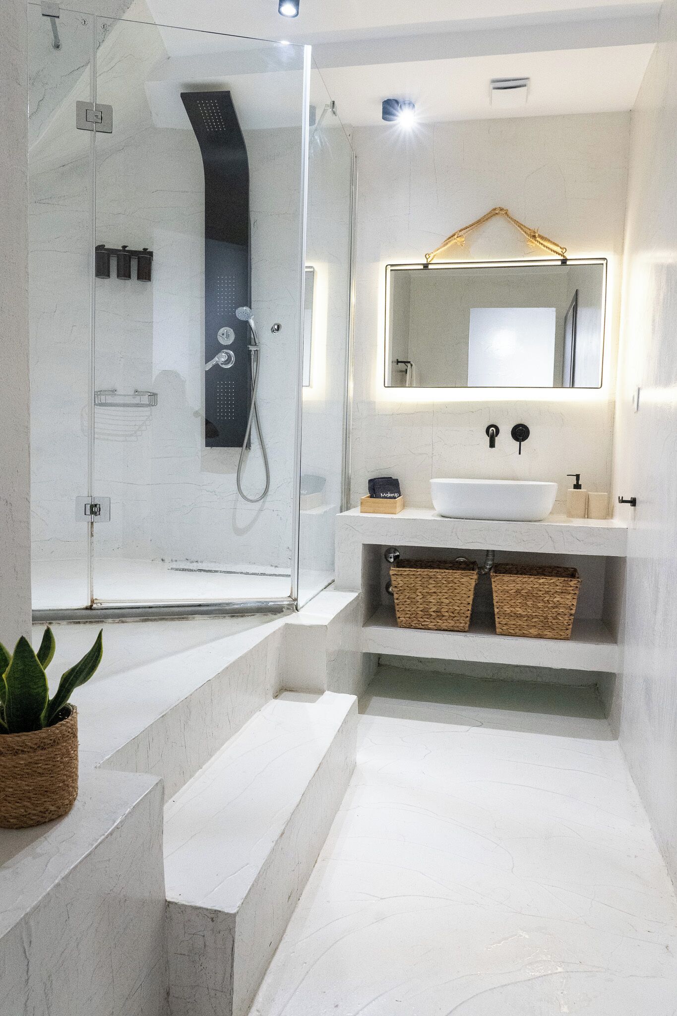 A modern bathroom with a glass-enclosed shower, a white sink, and a mirror with a gold frame.