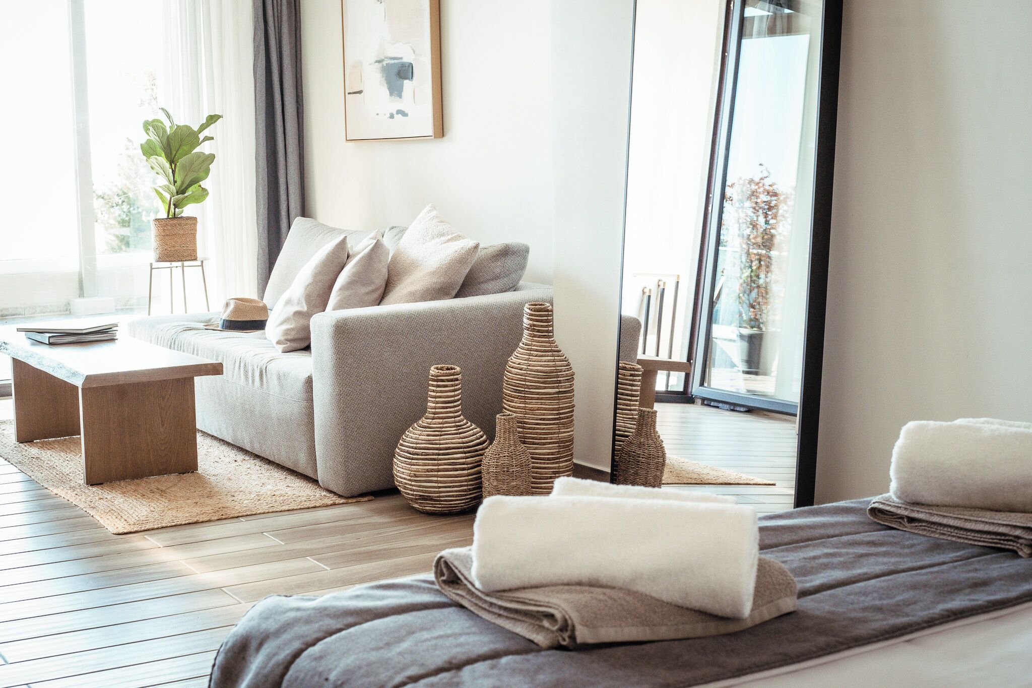 A modern living room with a sofa, a coffee table, a potted plant, and decorative vases.