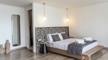 A modern bedroom with a wooden bed, a black and white patterned headboard, bedside tables, and a large mirror.