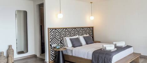 A modern bedroom with a wooden bed, a black and white patterned headboard, bedside tables, and a large mirror.