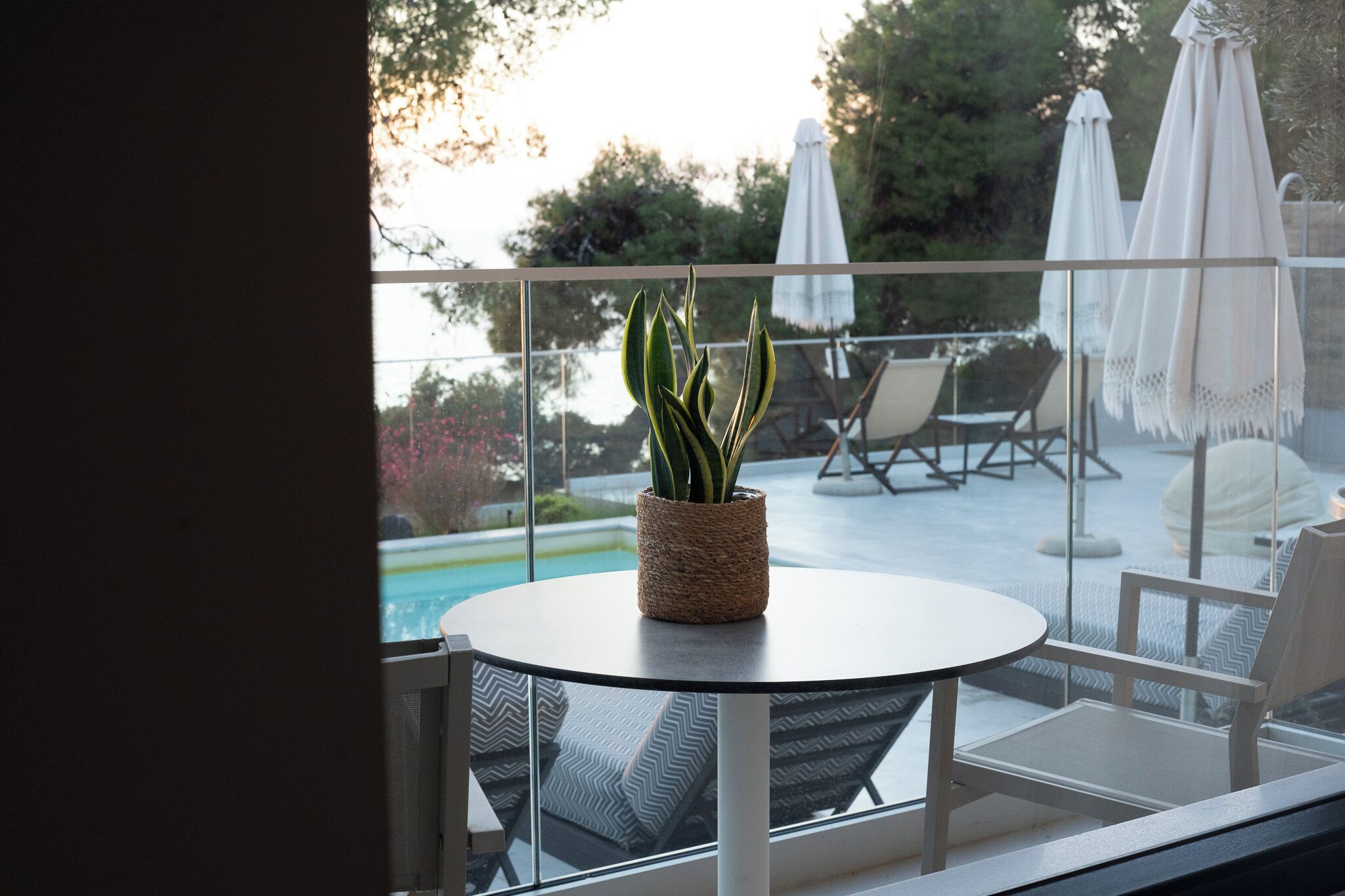 A balcony with a round table, a potted plant, and outdoor seating.