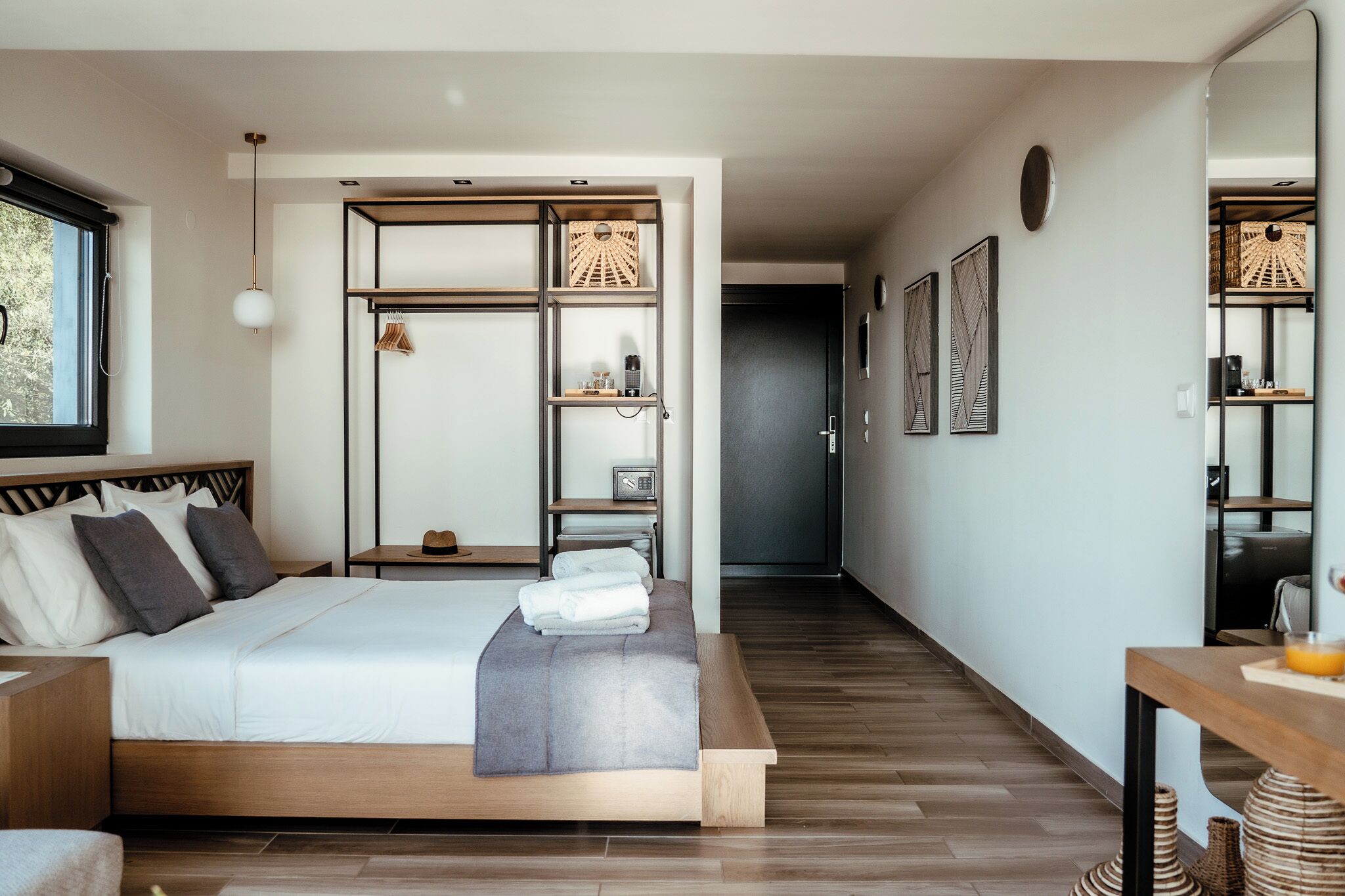 A modern bedroom with a large bed, a bedside table, a wardrobe, and a desk with a chair.