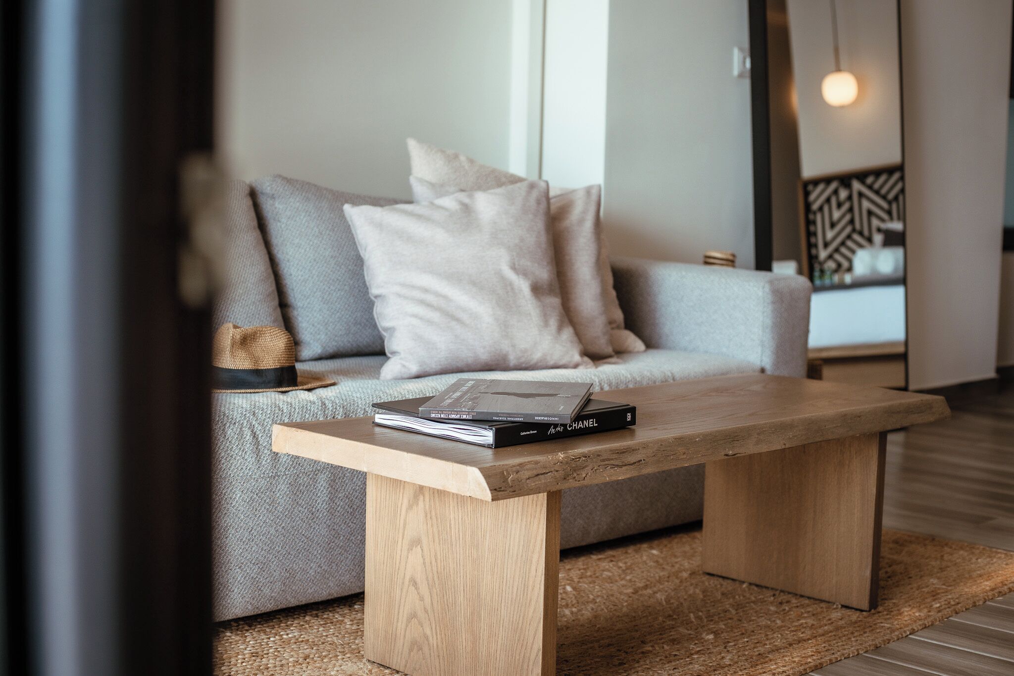 A modern living room with a sofa, a wooden coffee table, and a book titled 'AF CHANEL'.