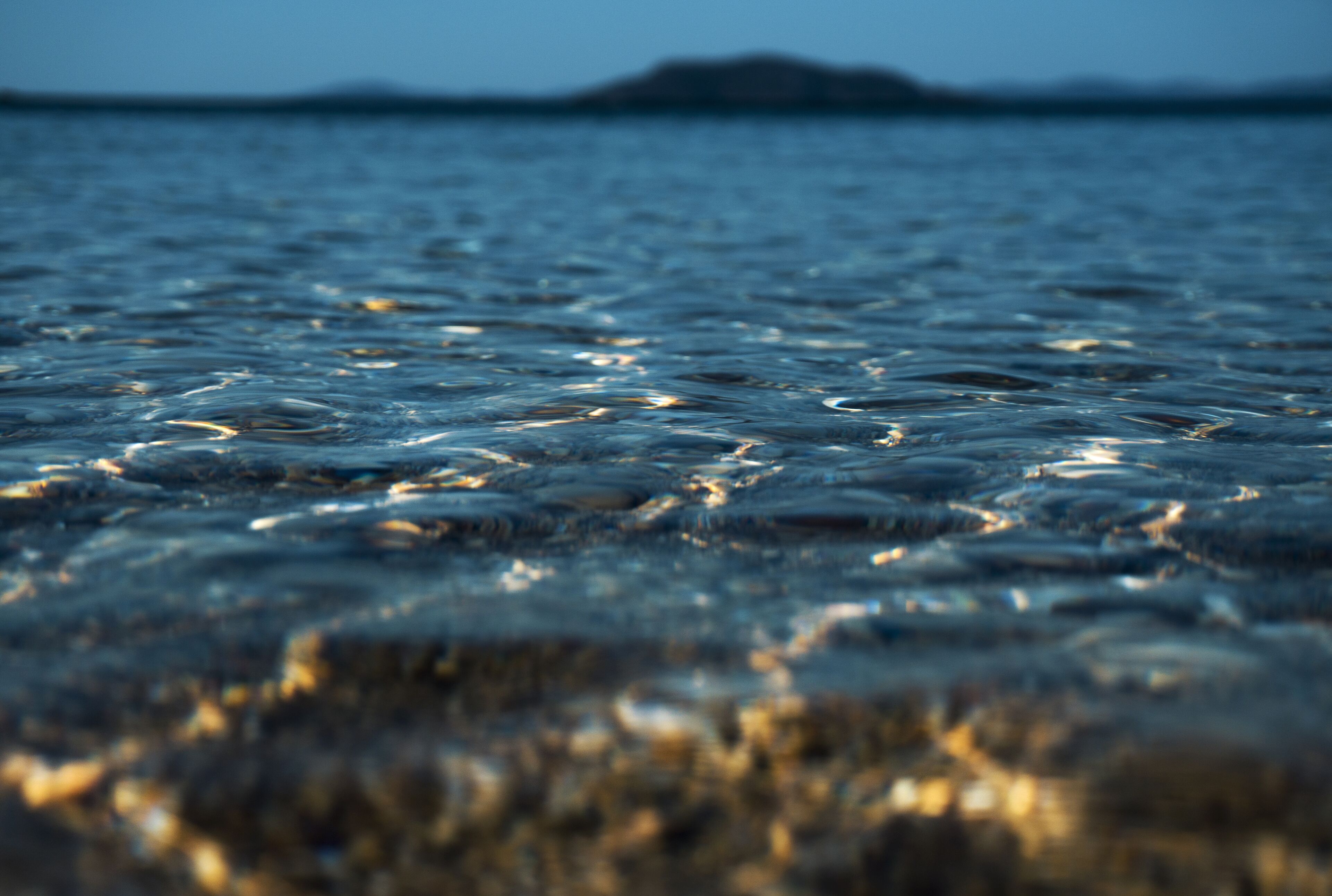 A close-up of water with ripples and a distant landmass.