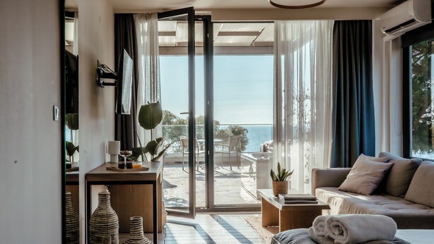 Una sala de estar moderna con un sofá, una mesa de centro y vistas al mar a través de amplios ventanales.