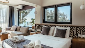 Una habitación de hotel moderna con una cama grande, un sofá y vista al mar.