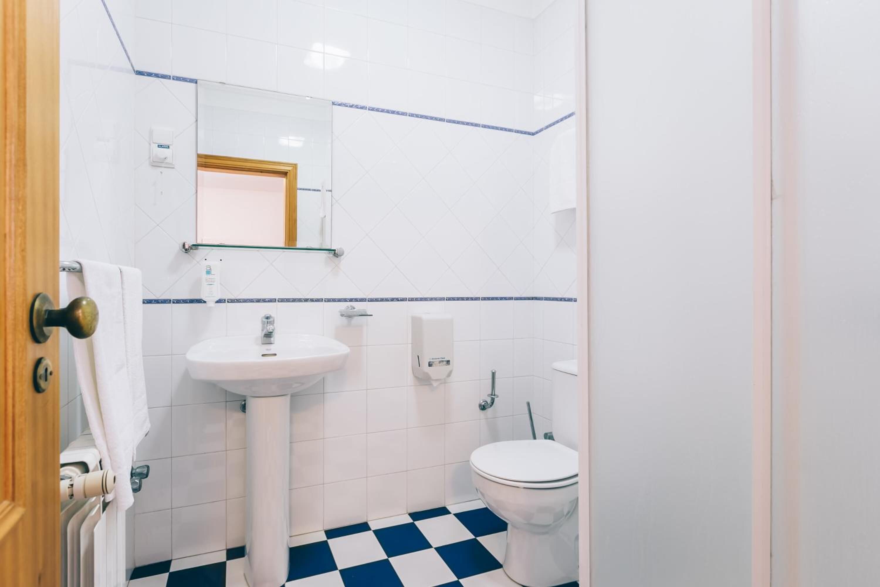 A bathroom with a white sink, toilet, and a mirror above the sink.