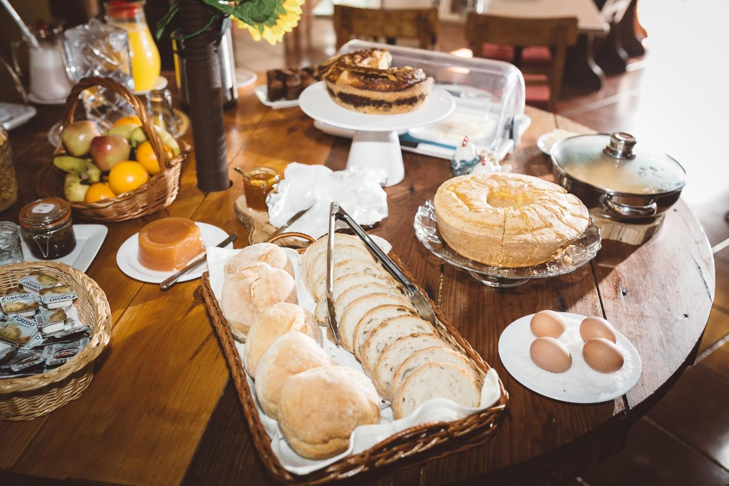 Un ricco buffet della colazione con pane, dolci e frutta assortiti.