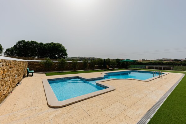 Una piscina al aire libre de temporada, sillones reclinables de piscina