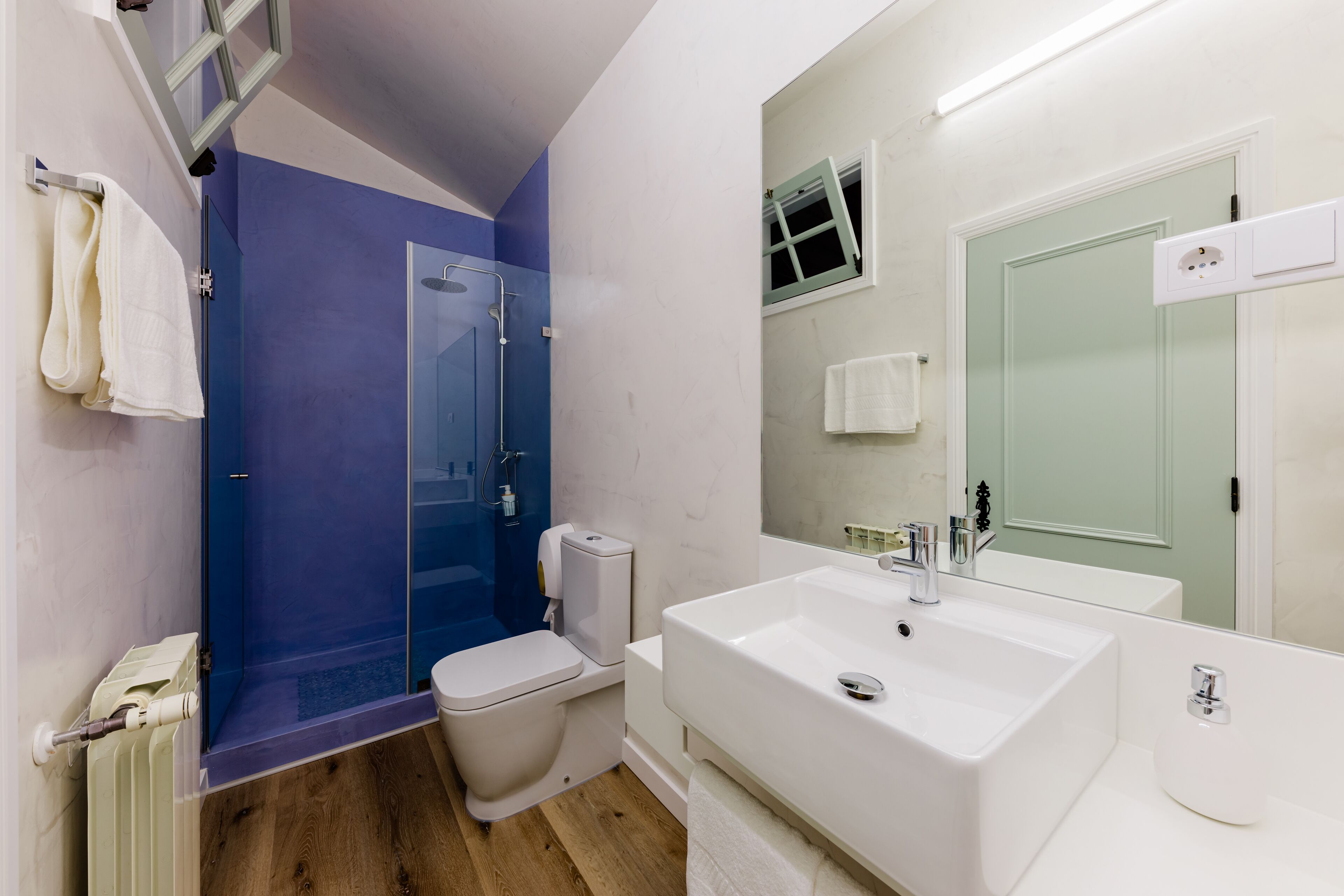 A modern bathroom with a glass shower enclosure, a white sink, and a toilet.