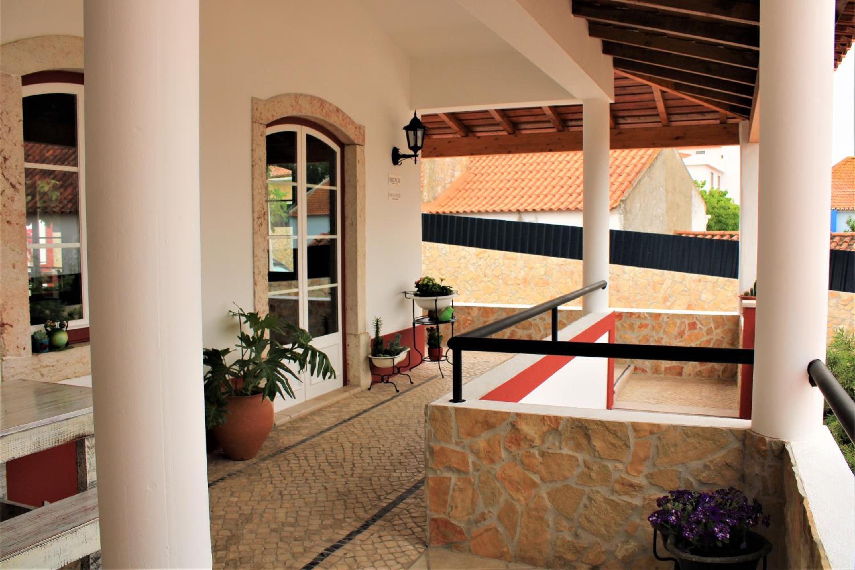A covered outdoor area with stone walls, a staircase, and potted plants.