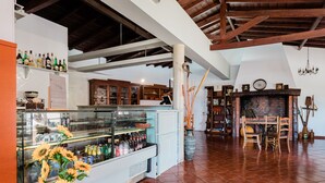 Interior de un restaurante con barra, vigas de madera, chimenea de ladrillo y mesa de comedor con sillas.