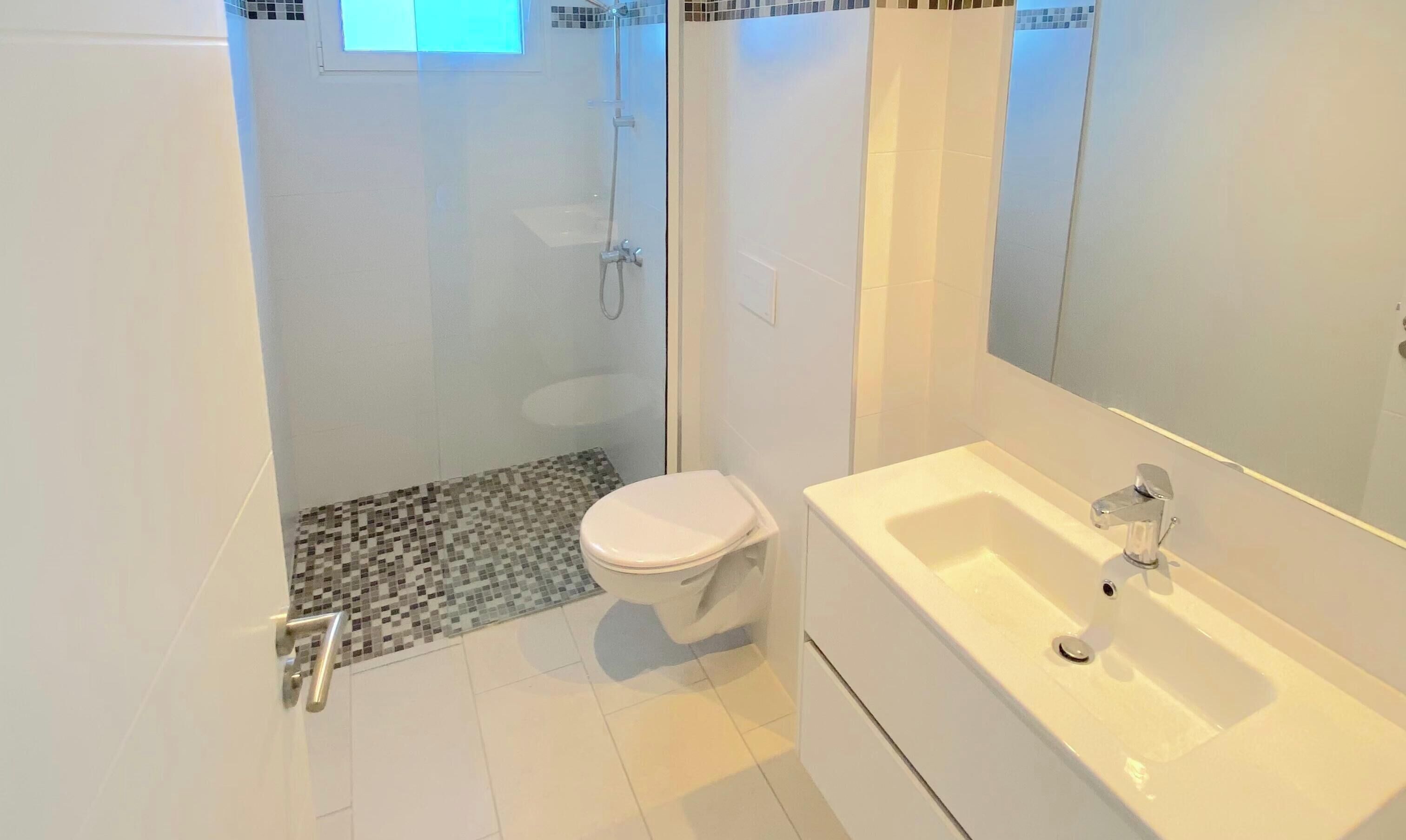 A modern bathroom with a shower, toilet, and sink.