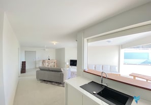Eine moderne Küche mit integriertem Spülbecken, einem Essbereich mit Tisch und Stühlen sowie einem großen Fenster mit Blick auf den Himmel.