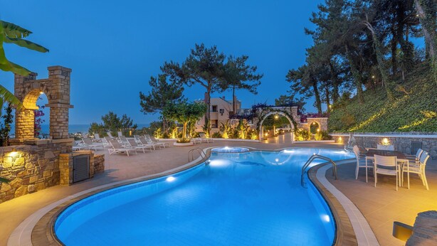 Ein Pool mit Liegestühlen, steinernen Bogen und Meerblick.
