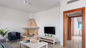 Ein modernes Wohnzimmer mit Kamin, Flachbildfernseher, Sofa und Couchtisch.