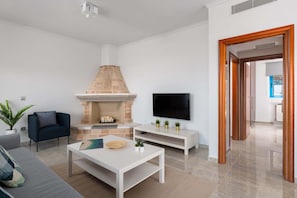A modern living room with a fireplace, a flat-screen TV, a sofa, and a coffee table.