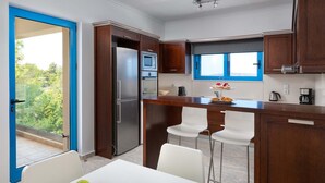 Eine moderne Küche mit Kühlschrank, Backofen, Mikrowelle und einem Fenster mit Blick auf Grünflächen.