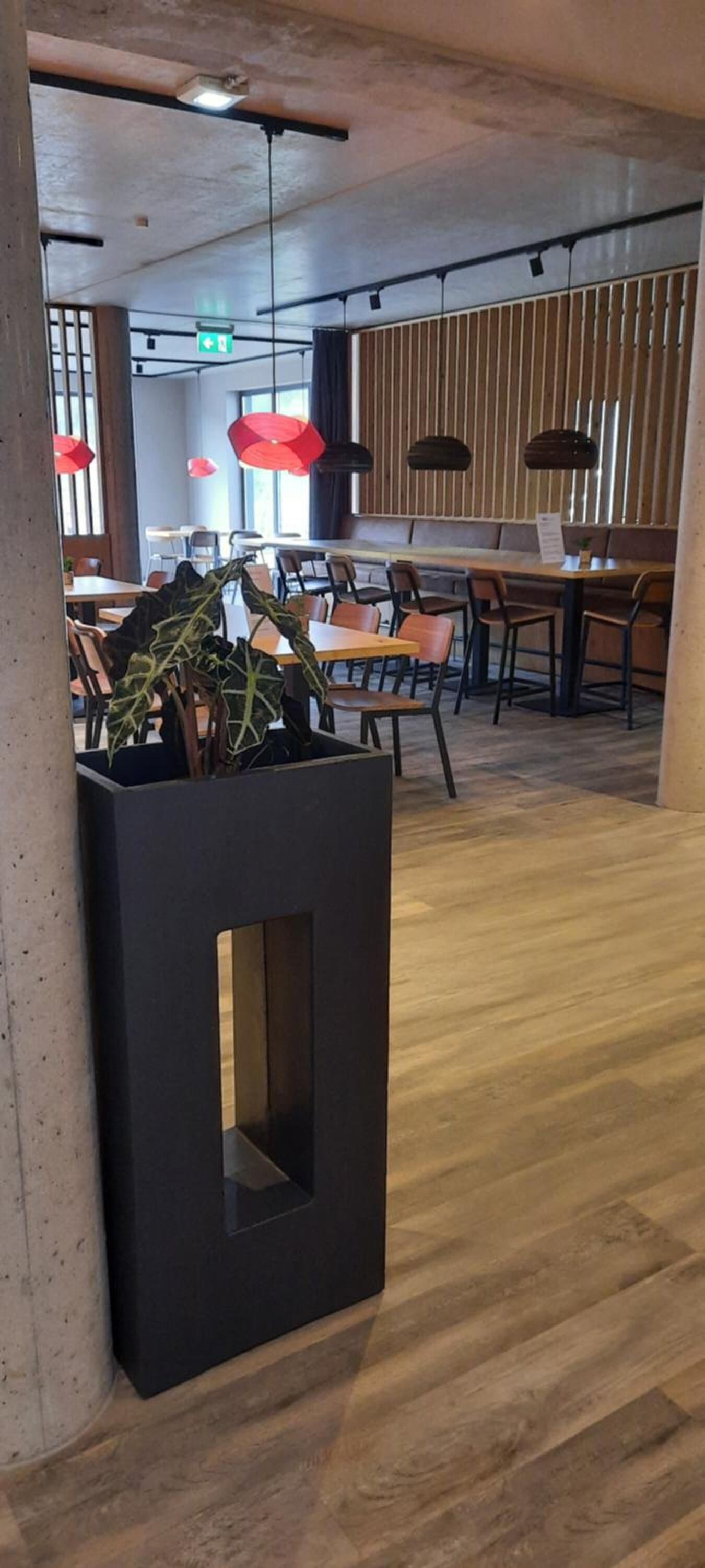 A modern interior with wooden flooring, black trash bins, and seating areas.