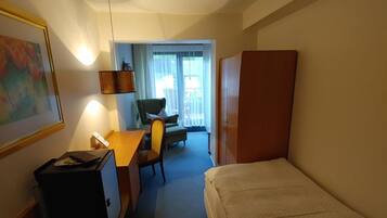 A hotel room with a bed, desk, chair, and a small cabinet.
