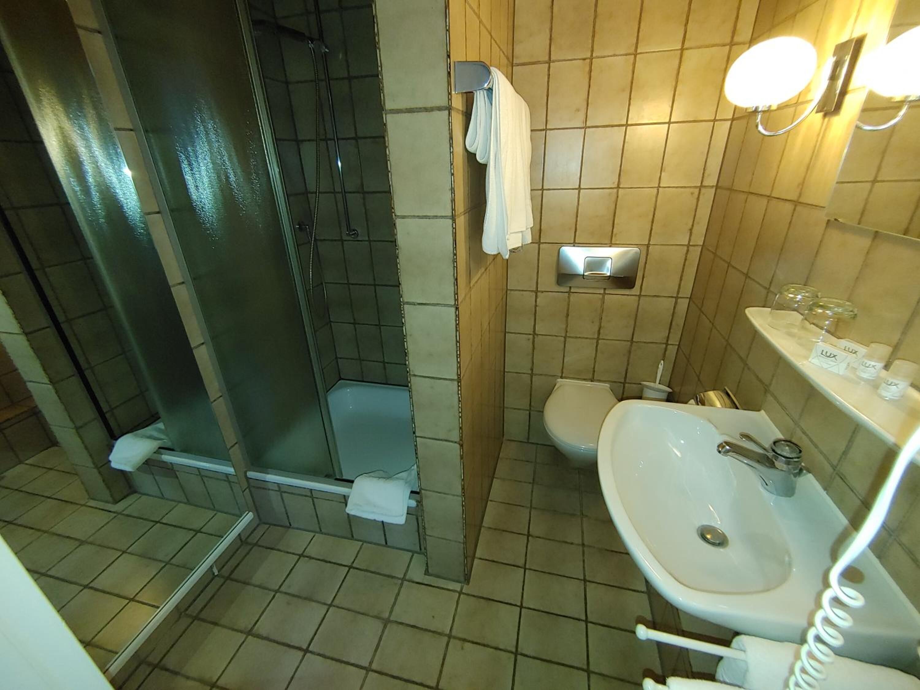 Un bagno con doccia, WC e lavandino.