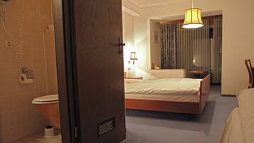 A hotel room with a bed, a bathroom, and a hallway.