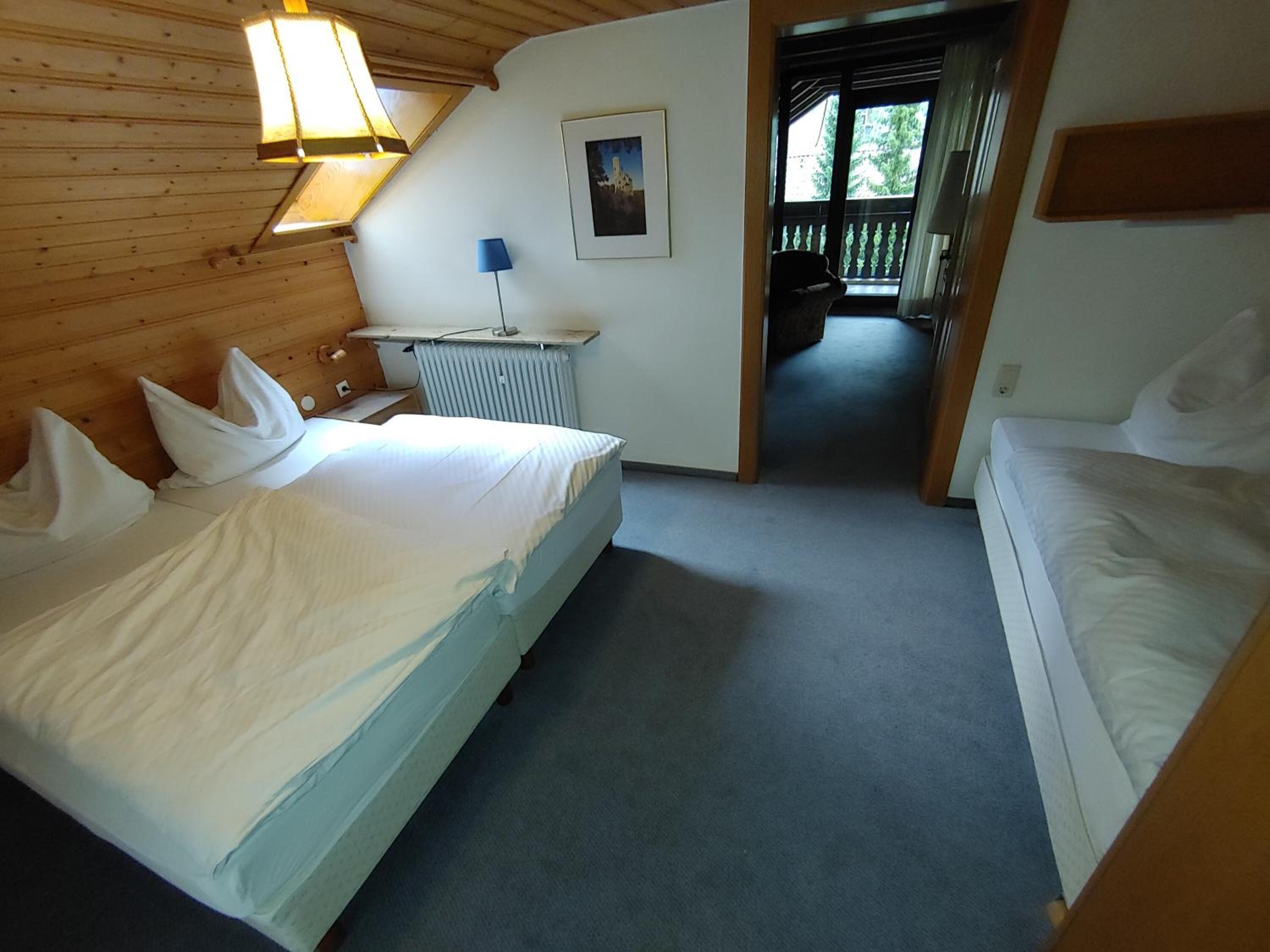 Una habitación con dos camas, un radiador, un escritorio, una lámpara y un cuadro en la pared.