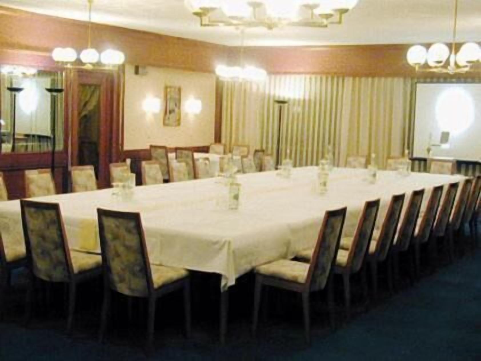 Ein Konferenzraum mit langem Tisch, Stühlen und einer Projektionsleinwand.