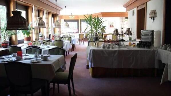 Un restaurante con varias mesas, sillas y lámparas colgantes.
