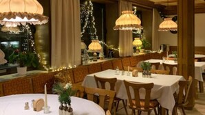 A restaurant with round tables, wooden chairs, and hanging lamps. - Hotel Adler (Lichtenstein)