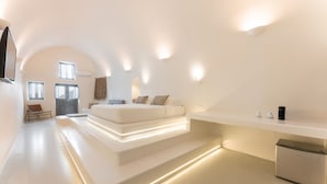 Un dormitorio moderno y minimalista con una cama grande, zona de estar integrada y un televisor de pantalla plana.