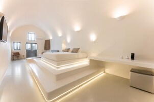 Un dormitorio moderno y minimalista con una cama grande, zona de estar integrada y un televisor de pantalla plana.