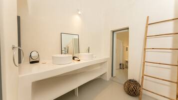 A modern bathroom with two sinks, a large mirror, and a wooden ladder.