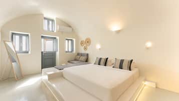 A modern bedroom with a large bed, a sofa, a desk, and a mirror.